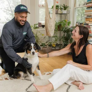 technician and customer inside home petting dog smiling