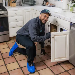 technician under kitchen sink with flashlight