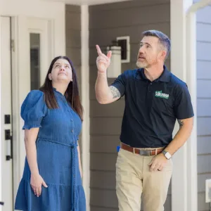 technician and customer outside in front of house looking up