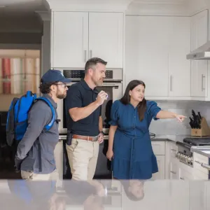 technicians and customer in kitchen pointing