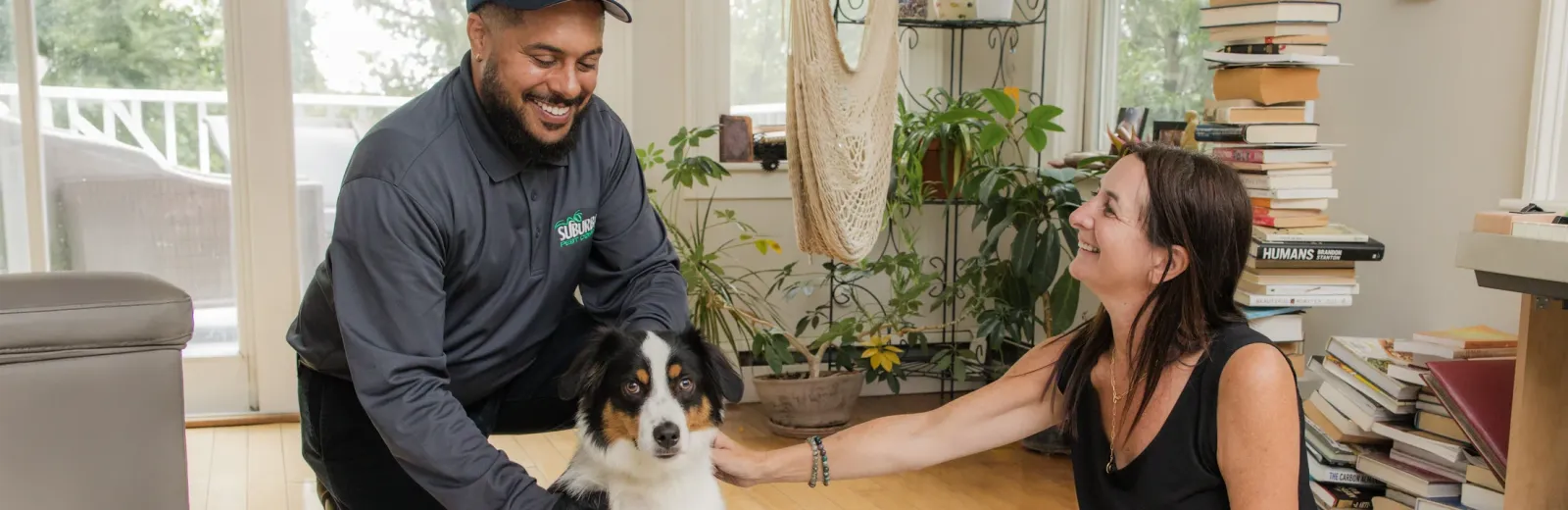 suburban pest technician and customer smiling with dog