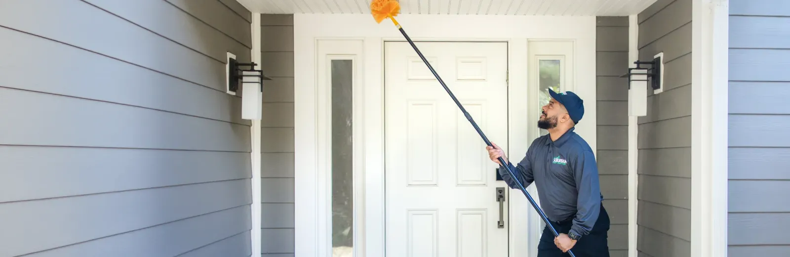 technician sweeping exterior of home