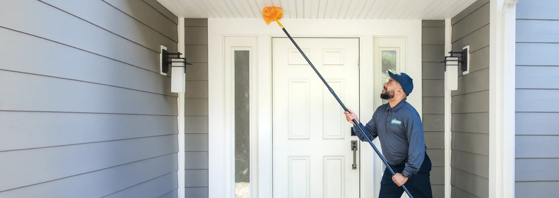 technician sweeping exterior of home