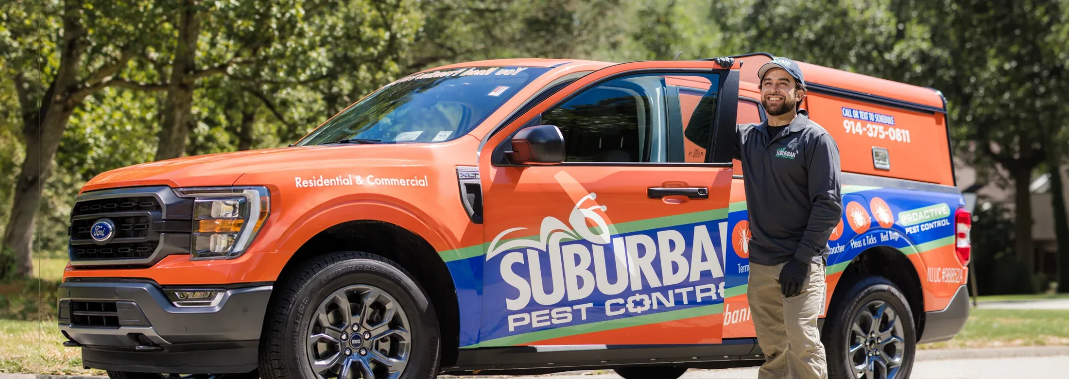 technician standing next to company truck smiling