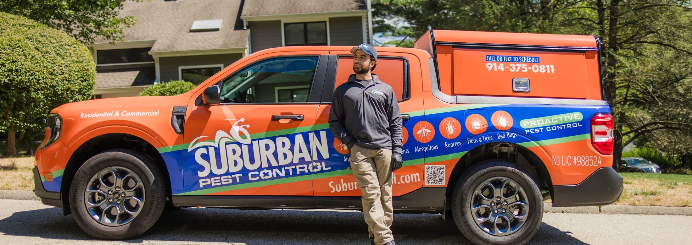 suburban pest control technician standing next to truck