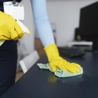 A person with yellow gloves cleaning a desk