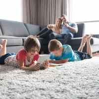 kids laying on the floor with their parents on the couch behind them