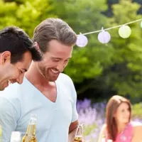 three men standing outside in front of a grill