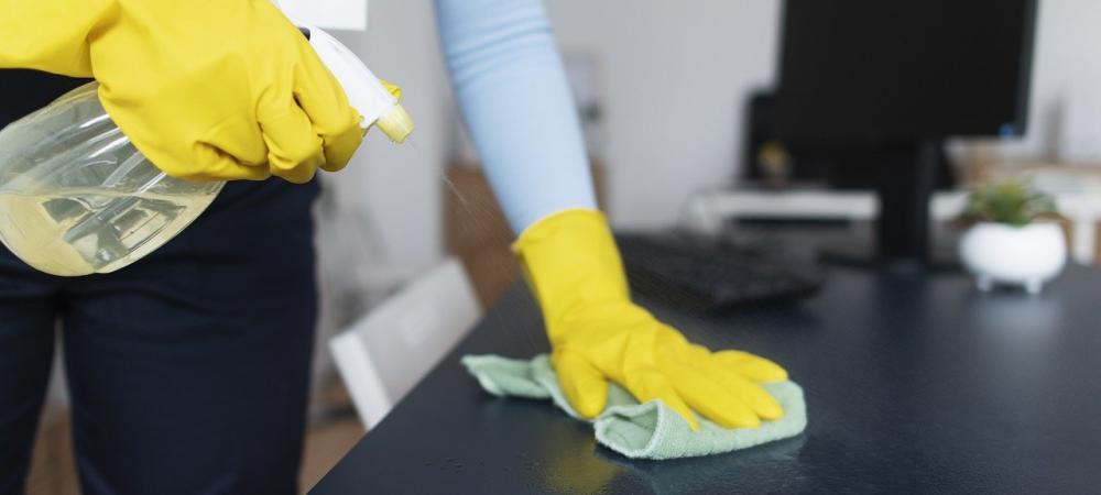 A person with yellow gloves cleaning a desk