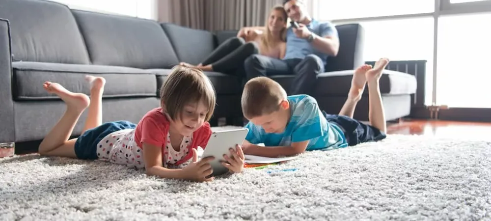 kids laying on the floor with their parents on the couch behind them