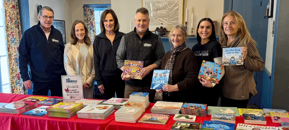 The Suburban Pest Control team with a table of books