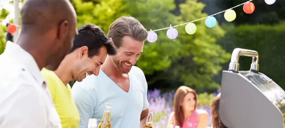 three men standing outside in front of a grill