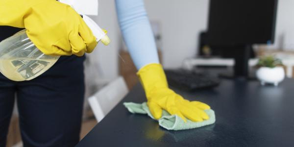 A person with yellow gloves cleaning a desk