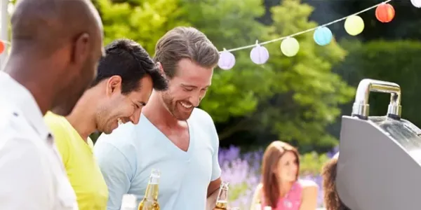 three men standing outside in front of a grill